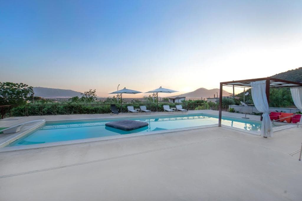 La piscina al tramonto con ombrelloni e montagne sullo sfondo